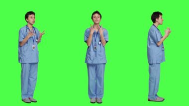 Stresli öfkeli hemşire, stüdyoda öfkesini ve öfkesini göstererek, yeşil perde arkaplanının karşısında birine bağırıyor. Agresif üzgün tıbbi asistan bağırıyor ve tatmin olmuyordu. Kamera A.