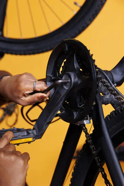 照片的焦点是双手使用多工具来调整和固定损坏的自行车零件 非洲裔美国人手持专家工具修理破碎自行车曲柄臂的详细图像 — 图库照片