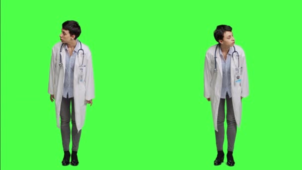 検査試験に患者が来るのを 探している女性医師が 緑色の背景に立っている人を 待っています 白いコート感覚の一般的な実践者 カメラ — ストック動画
