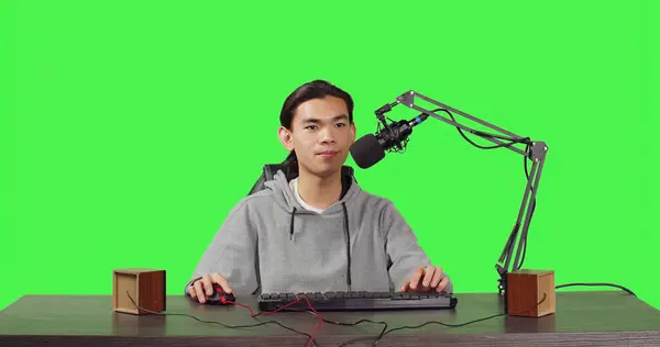 POV of vlogger broadcasting rpg gameplay over full body greenscreen in studio, content creator streaming live web contest. Asian video blogger playing games and broadcasting at desk.