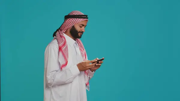 Homem Muçulmano Usa Trajes Tradicionais Joga Videogames Smartphone Sobre Fundo — Fotografia de Stock
