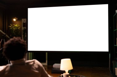 İzole ekran geniş akıllı TV 'yi abonelik temelli yayın hizmetleri serisi için kullanan kişi eğleniyor. BIPOC adamı rahatlıyor, VOD programlarının keyfini çıkarıyor.