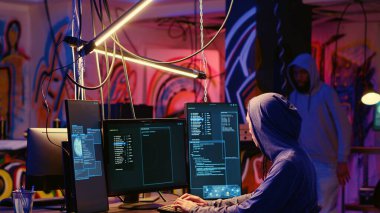 Yeraltı sığınağındaki hackerlar, bilgisayar sistemlerine sızıp değerli verilere ulaşmadan önce güvenlik duvarlarını aşmak için en iyi yaklaşımı bulmadan önce teknik bilgileri tartışıyorlar.