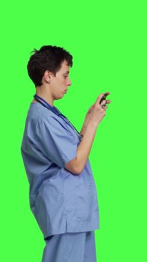 Profil Tıbbi Asistanı akıllı telefon uygulamasında mobil video oyunları oynuyor, sağlık hizmetlerine ara veriyor. Hemşire telefonda, yeşil ekran arkaplanının önünde duran bir oyun turnuvasından hoşlanıyor. Kamera B.