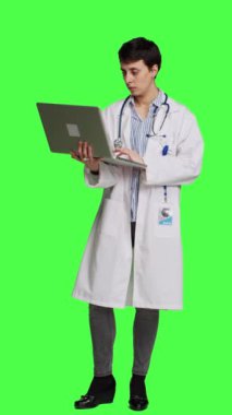 Önden bakan kendine güvenen doktor hastalıkları tedavi etmek için yeni ilaçlar arıyor, çevrim içi web sayfalarını yeşil ekran arka planına karşı taramak için dizüstü bilgisayar kullanıyor. Beyaz önlüklü doktor internet sitelerini kontrol ediyor