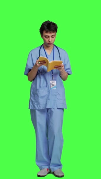 Visão Frontal Assistente Médica Lendo Livro Literatura Contra Pano Fundo — Vídeo de Stock