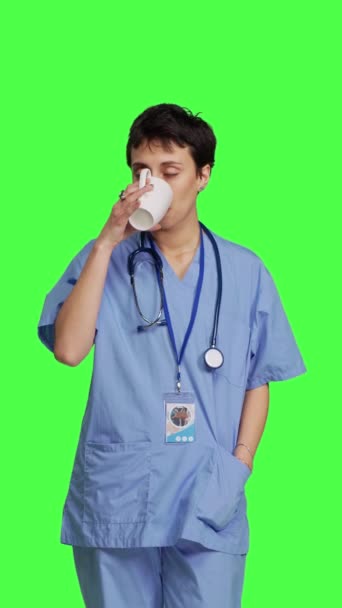 在预约考试前 医生助理先喝一杯咖啡 在绿屏的背景下享受咖啡因的清爽 护士喝饮料 摄像头B — 图库视频影像