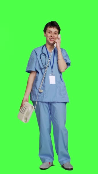 前景医疗助理在工作室通过固定电话与病人交谈 使用带电线的办公室复古电话与绿屏对接 护士接诊热线预约 — 图库视频影像