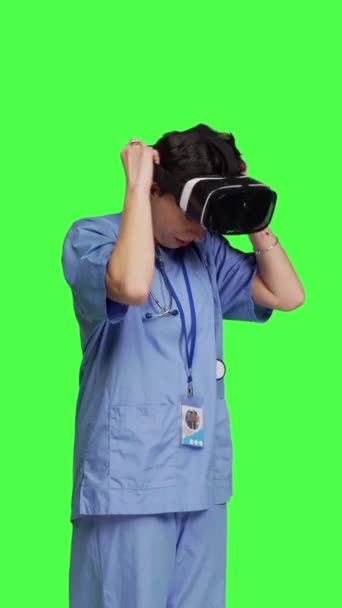 サイドビュー メディカルアシスタントは インタラクティブなVrメガネを使用して病気の治療をチェックし 仮想現実のヘッドセットとレンズを持つ患者の検査ファイルを調べます 緑色の背景に対する看護師 — ストック動画