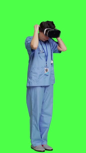 サイドビュー メディカルアシスタントは インタラクティブなVrメガネを使用して病気の治療をチェックし 仮想現実のヘッドセットとレンズを持つ患者の検査ファイルを調べます 緑色の背景に対する看護師 — ストック動画