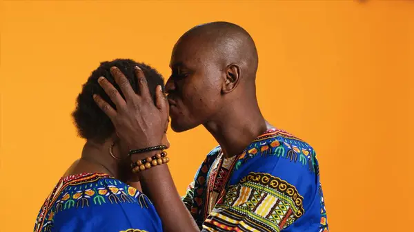 アフリカ系アメリカ人男性が妻の額をカメラでキスし 彼女の甘い愛情に対して誠実な気持ちを表現しています 夫はスタジオでロマンチックなジェスチャーをしている 彼のパートナーを気に — ストック写真