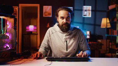 Adam oyun sandalyesini çeviriyor, canlı yayına başlıyor, izleyicileri selamlıyor, online rakipleri yenmek için stratejiler hakkında konuşuyor. Gülümseyen oyuncu RGB 'nin aydınlattığı oturma odasından canlı yayında hayranlarıyla sohbet ediyor.