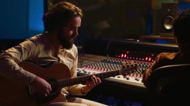 Profesyonel stüdyoda rock yıldızı gitarıyla müzik kaydediyor, kontrol odasında albümü için yeni bir müzik yaratıyor. Elektro akustik gitarda şarkı üreten sanatçı bestecisi. Kamera A.