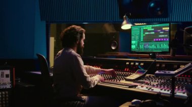 Kontrol odası ses mühendisi sürgülü ve düğmeli müzik düzenliyor, profesyonel ses geçirmez stüdyoda post prodüksiyon üzerinde çalışıyor. Müzik seti karıştırma konsolunda şarkı üreten teknisyen. Kamera B.