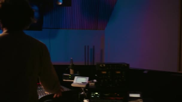 音楽プロデューサーは スタジオでコンソールとオーディオソフトウェアを混合し キーボタンを押し コントロールルームでノブをねじ曲げるトラックを編集します 音量を調整するサウンドエンジニア カメラ — ストック動画