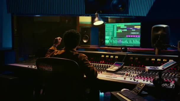非裔美国人音频工程师计算歌手在音箱 准备在控制室录制和处理曲目 制作人扭动旋钮和电唱机以提高曲调质量 摄像头B — 图库视频影像