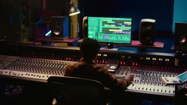 非裔美国人声音制作人在音频软件和控制台上编辑曲目 调整音量水平 增加后期制作效果 技师在工作室里制作新的流行歌曲 摄像头B — 图库视频影像