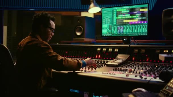 非洲裔美国音频技师的肖像在控制室使用混合控制台与旋钮和滑块 编辑录音并添加音效 熟练的音乐制作人在混音器 摄像头B — 图库视频影像