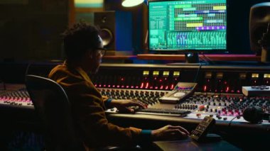 Kontrol odasındaki sesleri ses konsolu ve profesyonel kurgu yazılımı ile birlikte bilgisayarda takip ve karıştırma mühendisleri. Müzik prodüksiyon uzmanı motorlu faders ve knobs kullanıyor. Kamera A.