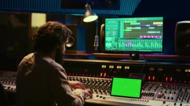 Müzik kayıt yazılımı ve kurgu melodileri ile çalışan ses teknisyeni, yapım sonrası stüdyoda konsol ve kontrol panelini karıştırıyor. Teknik ekipman üreticisi. Kamera B.