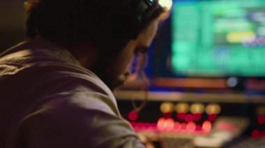 Genç besteci, gitar melodisini profesyonel stüdyoda kaydederek konsol ve daw yazılımının karışımında yeni bir müzik besteledi. Sanatçı, kontrol odasında yeni şarkılar söylüyor. Kamera A.