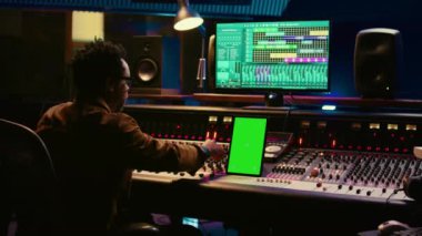 Afro-Amerikan ses teknisyeni, plakları yeşil ekranla karıştırıp düzenliyor ve profesyonel prodüksiyon stüdyosunda çalışıyor. Yapımcı, albümü için yeni şarkılar yaratıyor. Kamera B.