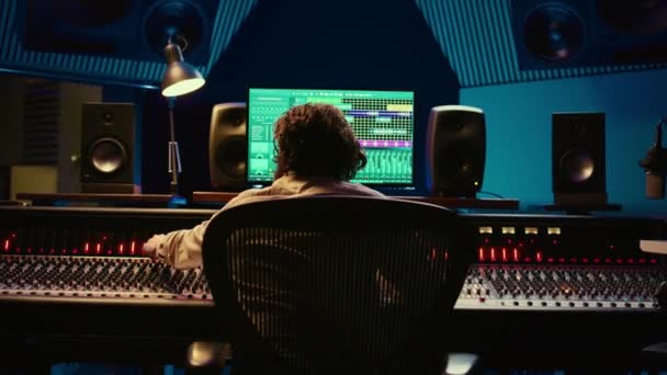 オーディオエキスパートはスタジオでデジタル編集ソフトウェアを使用してトラックをミックスしてマスタリングし 新しい音楽を作成します スイッターやファッションを使用して音量レベルを調整する熟練サウンドデザイナー カメラ — ストック動画