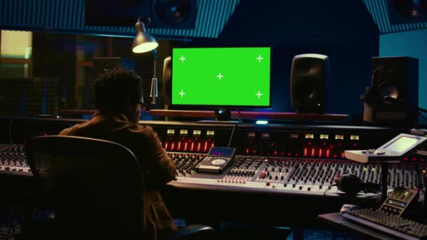 非裔美国人音乐制作人在Pc上与绿屏合作 在控制室使用混音控制台进行混音和主控 音频技术员用旋钮和开关记录音轨 摄像头B — 图库视频影像