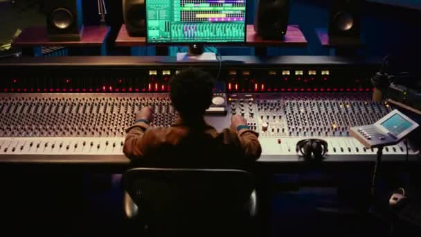 非裔美国人声音工程师记录和编辑曲目后生产 使用混合控制台与旋钮和交换器 熟练的音频技师在录音室生产新的音乐 摄像头B — 图库视频影像