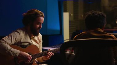 Performans yazarı elektro akustik gitarıyla yeni şarkılar söylüyor ve prodüksiyon sonrası yeni şarkılar kaydediyor. Stüdyoda ses mühendisiyle işbirliği içinde çalışan bir müzisyen. Kamera A.