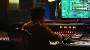 Afrikalı Amerikalı ses tasarımcısı, ses tonlarındaki dengesizlikleri ve kaydedilen dosyalardaki beyaz gürültüyü ortadan kaldırıyor. Müzik endüstrisi profesyonel stüdyoda prodüksiyon yapıyor. Kontrol odası uzmanı rayları düzenliyor. Kamera A.