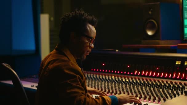 非洲裔美国音频技师的肖像在控制室使用混合控制台与旋钮和滑块 编辑录音并添加音效 熟练的音乐制作人在混音器 相机A — 图库视频影像