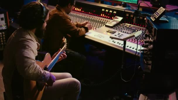 才能あるギタリストがプロのスタジオでライブパフォーマンスを行い コンソールアンプのミキシングに新しいトラックを記録 新しい歌を演奏し 音楽を創造する若いアーティスト カメラ — ストック動画