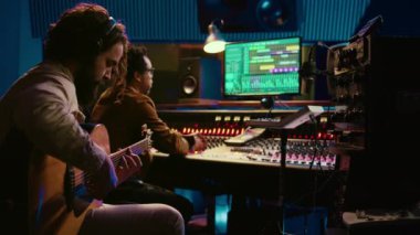 Genç besteci, gitar melodisini profesyonel stüdyoda kaydederek konsol ve daw yazılımının karışımında yeni bir müzik besteledi. Sanatçı, kontrol odasında yeni şarkılar söylüyor. Kamera B.