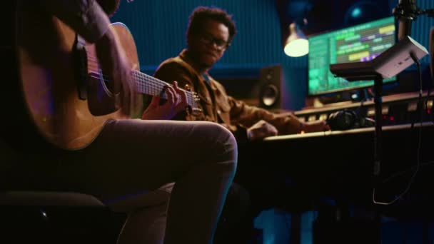 有创意的音乐家在专业的录音室里唱吉他 和制作人一起录制他的曲目 歌手作曲家为他的专辑创作了一首新歌 在控制台上编辑曲调 摄像头B — 图库视频影像
