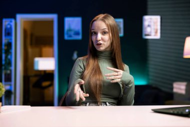 Daire stüdyosunda online yayın kanalı için içeriği filme çeken genç hayranların portresi. Gen z etkileyicisi evde masada oturuyor, abonelerle iletişim kuruyor