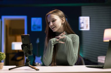 Neşeli Z jeneratörü, vlog kanalı için giriş bölümünü çekmek için cep telefonunu tripodun üzerinde kullanır. Neşeli genç internet yıldızı hayranları için video konusunu sunmaktan heyecan duyuyor