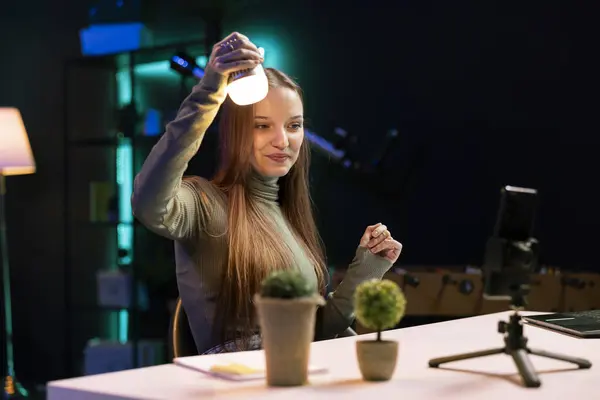 在霓虹灯照亮的工作室里 乐观的影响者对灯泡的拍摄评论能够转变为不同的颜色 微笑基因Z技术专家介绍了由语音命令控制的智能家庭自动化技术 — 图库照片