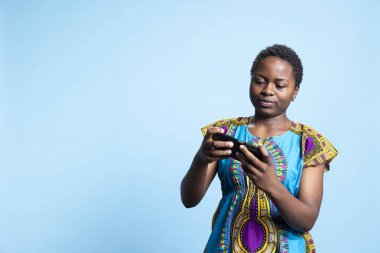 Çevrimiçi video oyunları şampiyonasına katılan neşeli insan stüdyoda mobil oyun oynuyor. Etnik giysili bir kadın oyun turnuvasında eğleniyor, sıradan bir oyuncu..