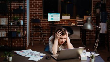 Businesswoman working on company project overnight, feeling frustrated, putting head in hands. Upset employee sighing while looking over figures on laptop screen, exasperated by failure clipart