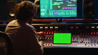 Müzik kayıt yazılımı ve kurgu melodileri ile çalışan ses teknisyeni, yapım sonrası stüdyoda konsol ve kontrol panelini karıştırıyor. Teknik ekipman üreticisi. Kamera A.