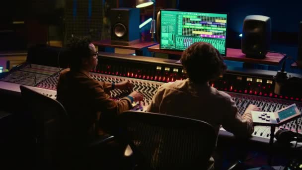 多样化的团队合作在控制室创作了一首新的流行歌曲 并在后期制作中混合和掌握了声音 艺术家和音频专家编辑音量水平和声音设置 摄像头B — 图库视频影像