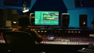Ses tasarımcısı ses seviyesini karıştırıcı kontrol masasında ayarlıyor, profesyonel müzik stüdyosu konsepti. Yapımcı sesi açar ve miksaj konsoluna efekt ekler ekler, canlı şarkılar kaydeder. Kamera B.