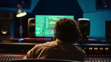 Neşeli, enerjik ses mühendisi profesyonel stüdyoda kendi müzik yaratımı üzerine dans ederek konsol ve daw yazılımının karışımını düzenliyor. Ses tasarımcısı işleme parçaları. Kamera B.