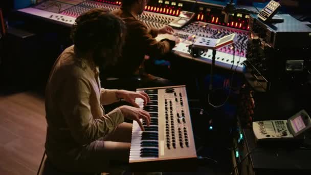 熟练的歌手在电子Midi控制器上录制歌曲 用钢琴演唱 并与音频工程师一起创作曲目 年轻的音乐家作曲家在控制台上编辑音乐 摄像头B — 图库视频影像