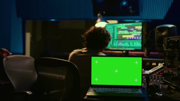 艺术家和音响设计师作为一个团队 生产新的曲目 绿屏笔记本电脑 音乐家和音频技师在音乐方面进行合作 在音频控制台上与机动爱好者混合 摄像头B — 图库视频影像