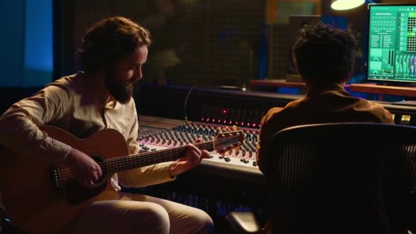 크리에이 아티스트는 자신의 기타를 노래하여 새로운 트랙을 녹음하여 스튜디오에서 제어실에서 — 비디오