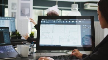 Mühendislik tasarımcısı, yeni kat planının mimari planlarını inceleyerek odaları ve düzeni değiştirmeye çalışıyor. İç tasarımda uzman teknisyen birlikte çalışma alanında çalışıyor..