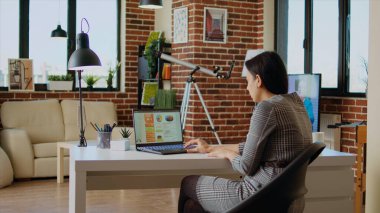 Evden çalışırken arka planda ses olarak televizyonla piyasa performans grafiklerini optimize eden uzaktan çalışan bir çalışan. Çevrimiçi iş analizlerini, istatistiksel veri ölçümlerini, kamera A 'yı kontrol eden telgraf çalışanı