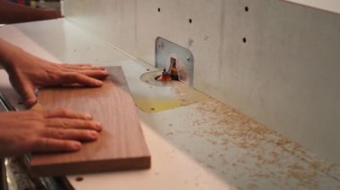 Stüdyodaki marangoz, ahşap parçaların kenarlarını pürüzsüz hale getirerek odun kalıbını delip geçiyor. Marangozhanedeki marangoz, ağır makineler kullanarak mobilya eklemleri ve kamera B 'yi kapatıyor.